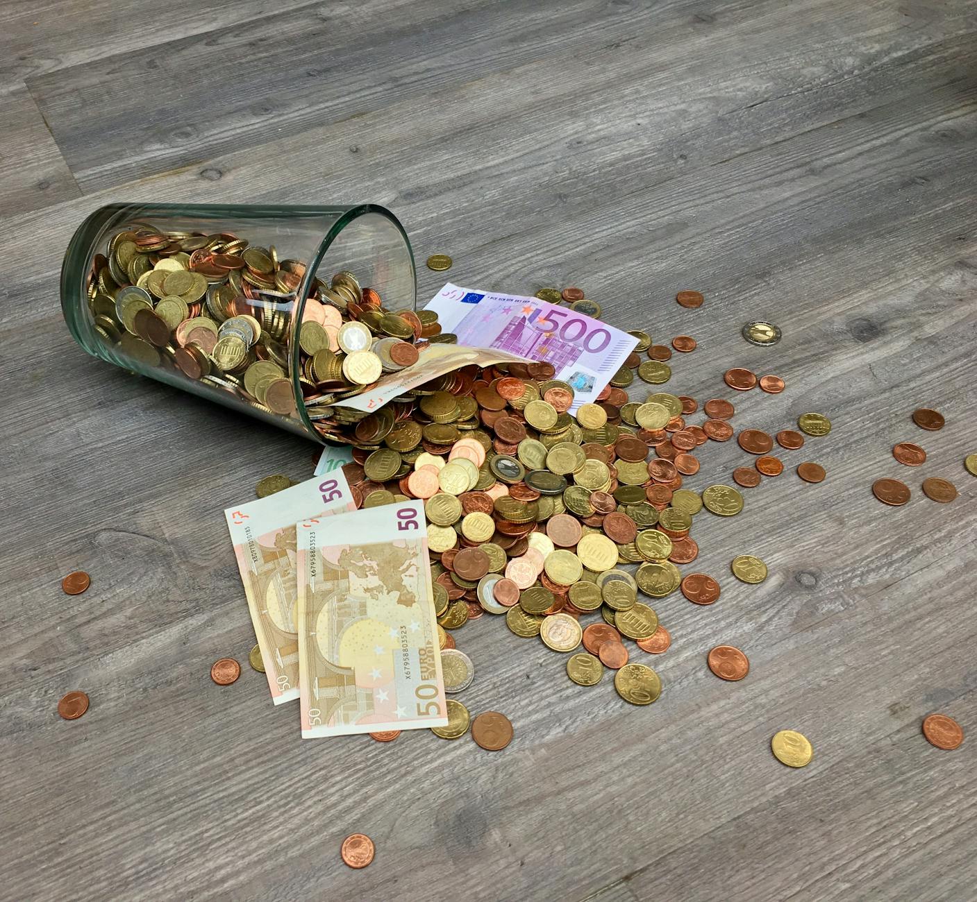 傳承的十字路口:不動產移轉與房地合一稅的終極指南 coins and banknotes scattered on gray wooden surface